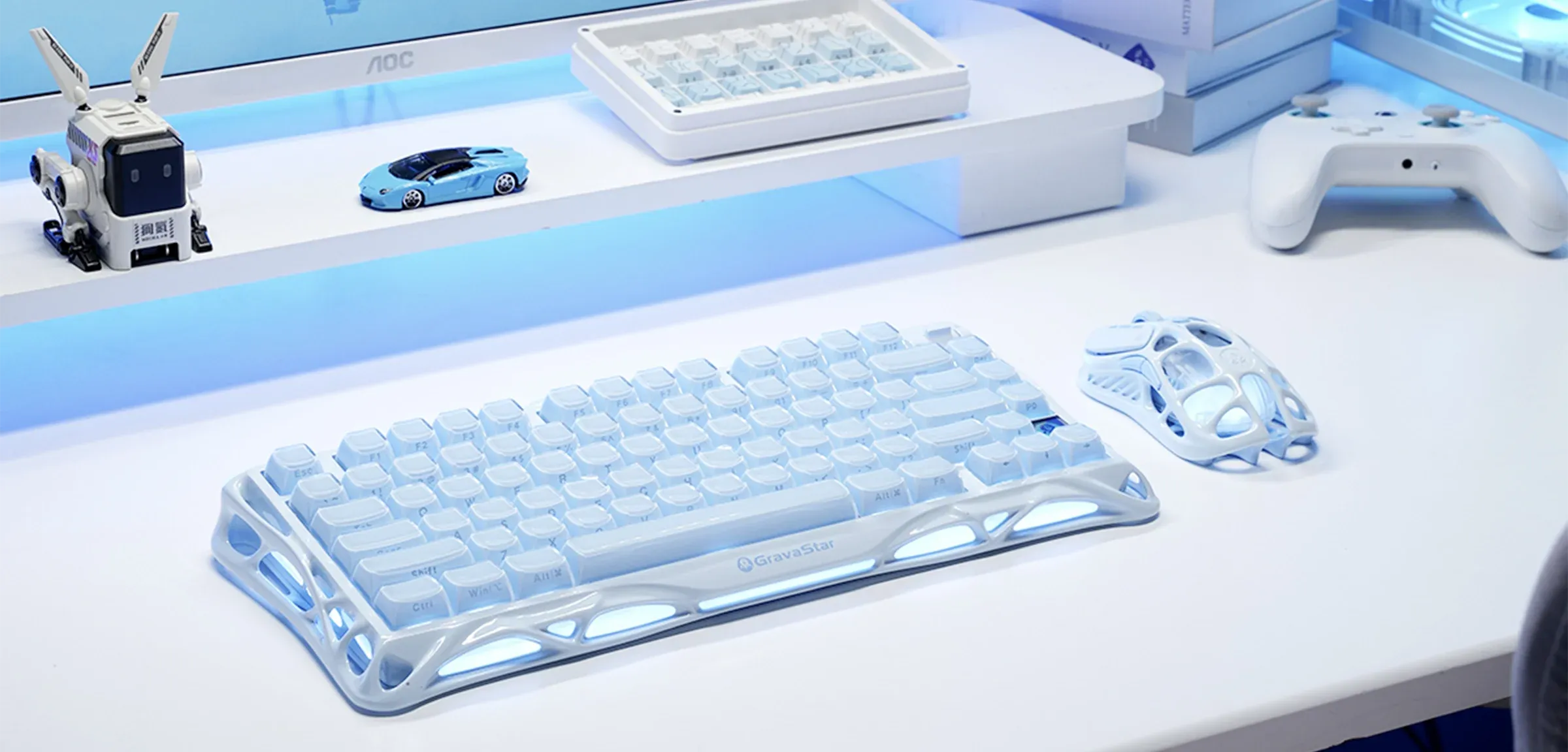 GravaStar Mercury M1 Pro Special Edition Ice Blue wireless gaming mouse displayed on white desk setup featuring lightweight magnesium alloy skeletal frame, PAW3395 26K DPI optical sensor, 4KHz polling rate support, and ice blue RGB lighting.