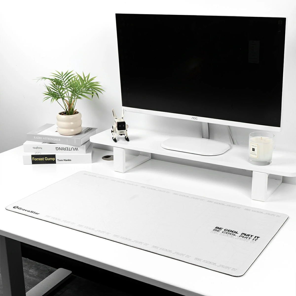GravaStar Gaming Mouse Pad White extended cyberpunk deskmat studio setup view featuring waterproof micro-weave surface, BE COOL PLAY IT slogan, Alpha65 charger, and white monitor stand on white desk.