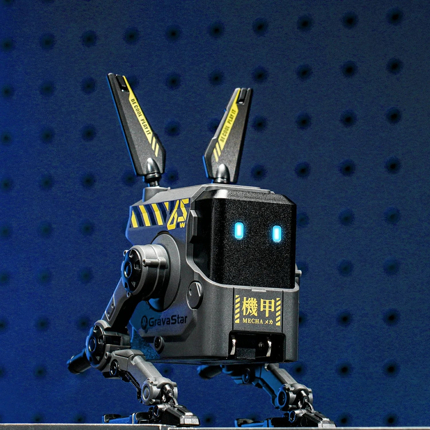GravaStar Alpha65 Charcoal Gray 65W GaN fast charger studio pegboard robot standing view featuring sleek matte black finish, transformable tripod stand, dual antennas, ice blue RGB eyes, and 3 USB ports, perfect paired with Mercury X Air Onyx Crystal mouse and Mercury K1 Stealth Black keyboard.