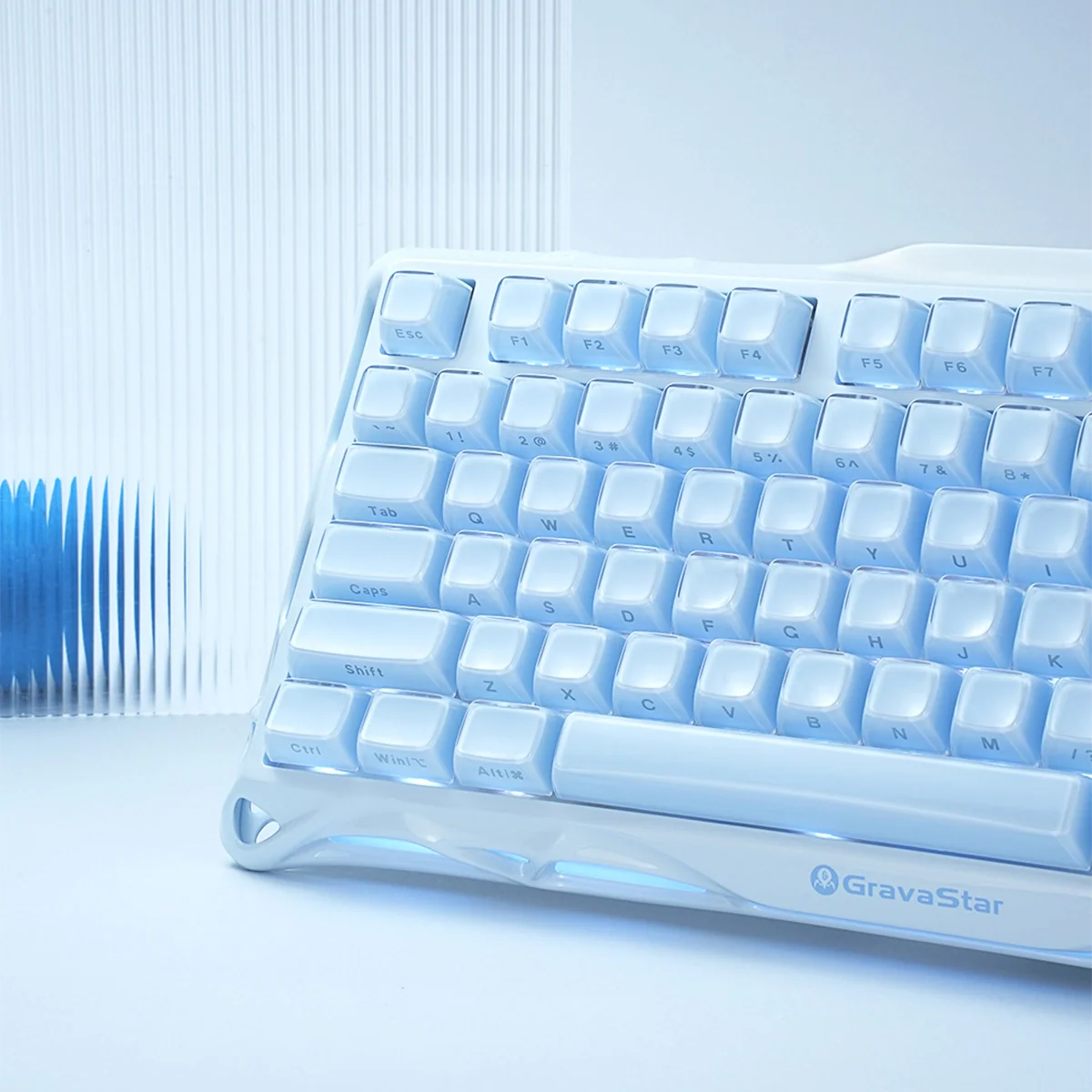 GravaStar Mercury K1 Ice Blue Edition 75% mechanical gaming keyboard – Side angle close-up showing ice blue aluminum alloy frame, translucent white keycaps, custom linear switches, and GravaStar logo branding.