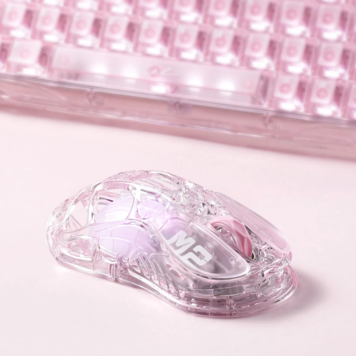 GravaStar Mercury M2 Crystal Rose 2024 Red Dot Award winner translucent wireless gaming mouse setup view paired with Mercury V60 Crystal Rose keyboard, featuring 88g skeletal frame, PAW3395 26K DPI sensor, 1000Hz polling rate, and RGB lighting.