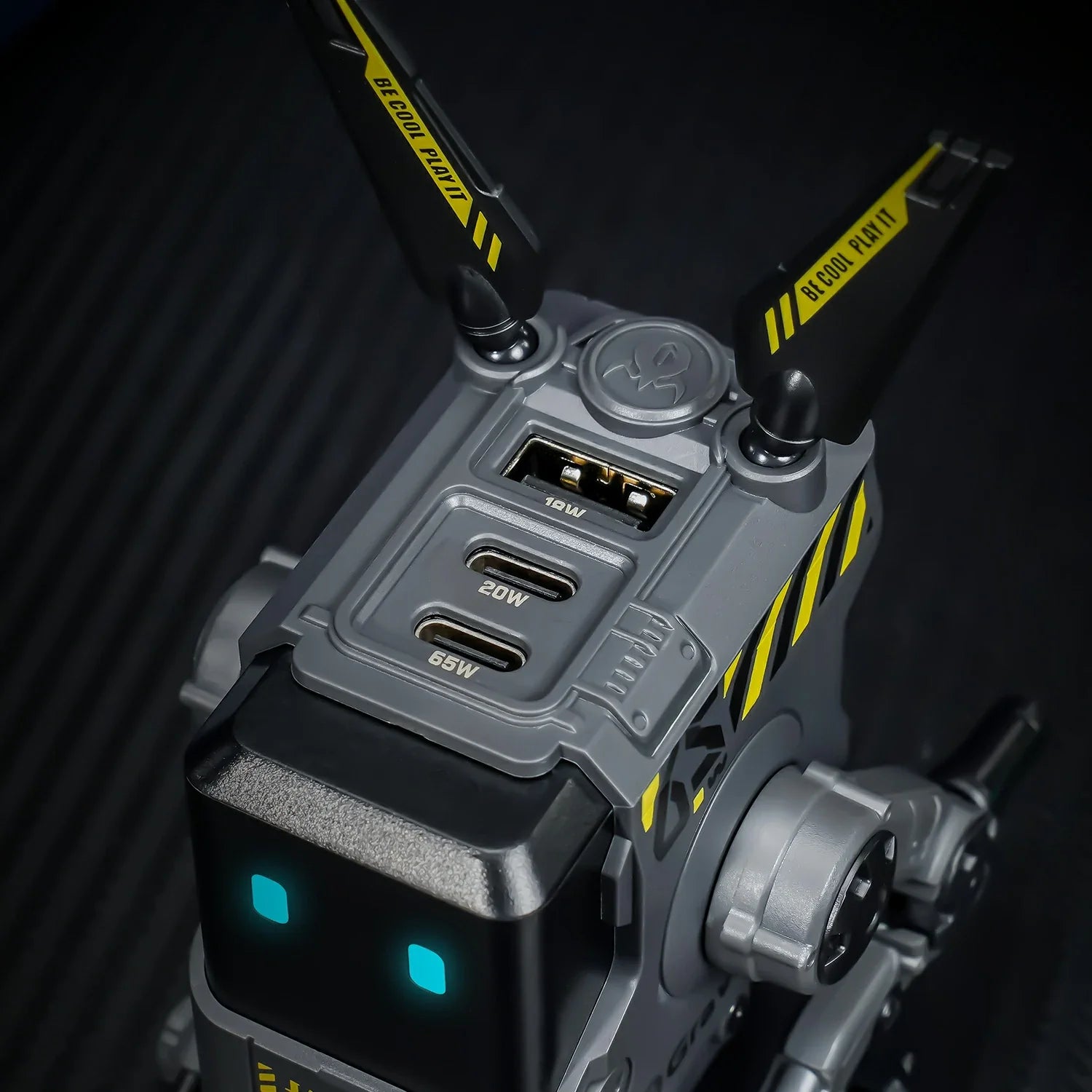 GravaStar Alpha65 GaN 65W Wall Charger Charcoal Gray top close-up view showing 3 USB ports (2 USB-C PD + 1 USB-A), tactical antennas with BE COOL PLAY IT slogan, and ice blue RGB eyes.