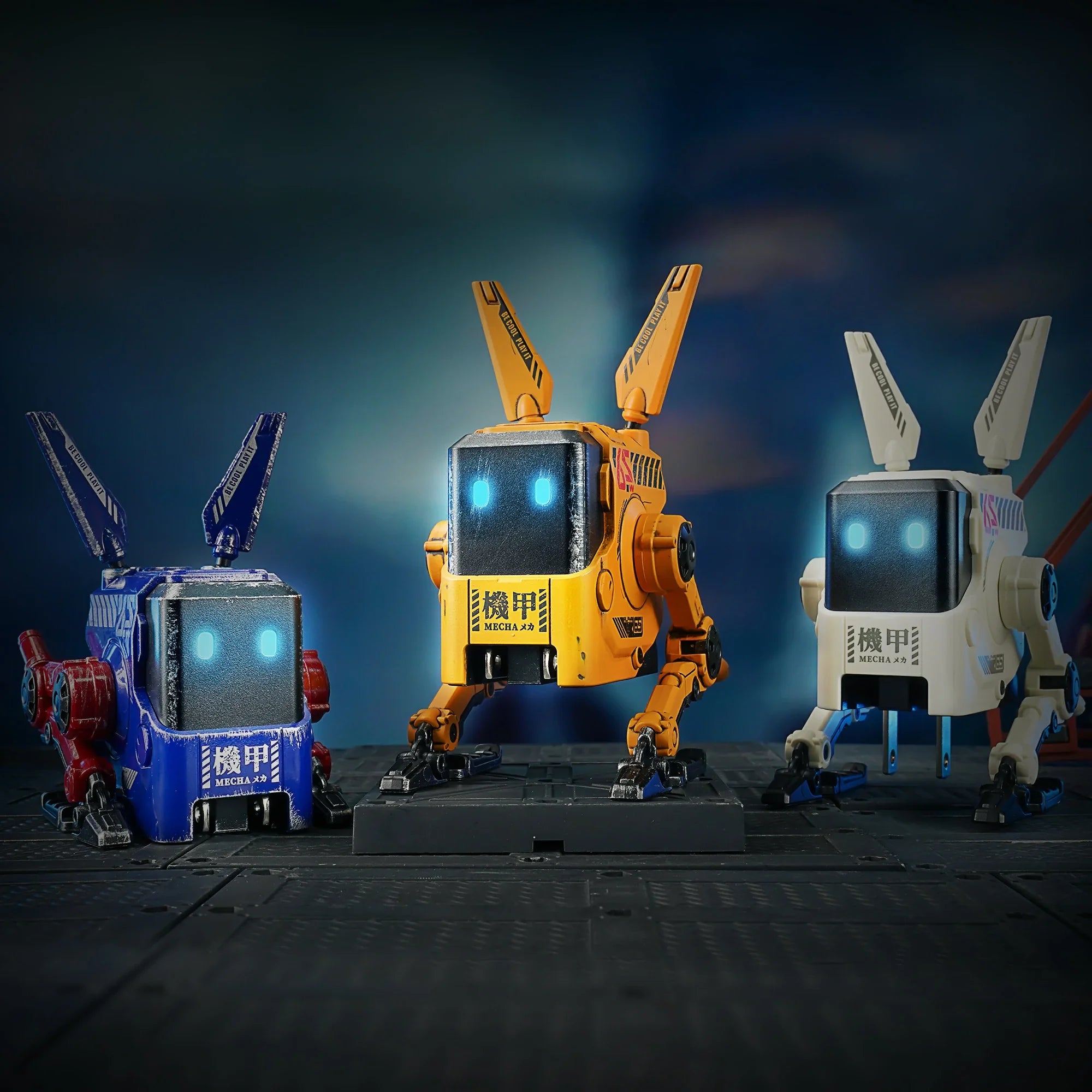 GravaStar Alpha65 GaN 65W Wall Charger studio group view featuring three mecha colorways including War-Damaged Yellow, Charcoal Gray, and special edition robot chargers with ice blue RGB eyes.