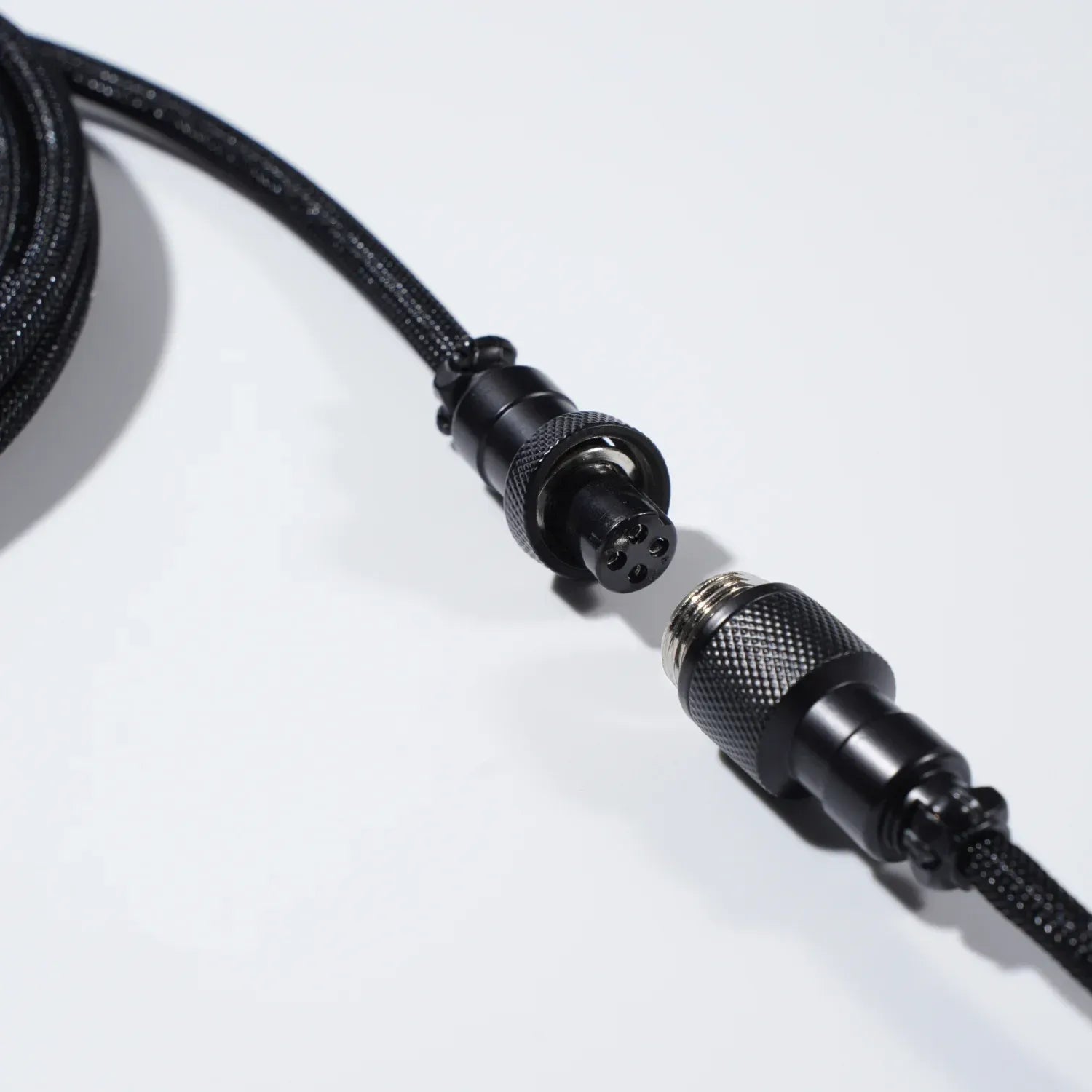GravaStar Coiled Aviator USB Cable Black macro close-up view displaying 4-pin GX12 nickel-plated metal aviator connector detachable structure and TPU EVA double-sleeved braided cable body.