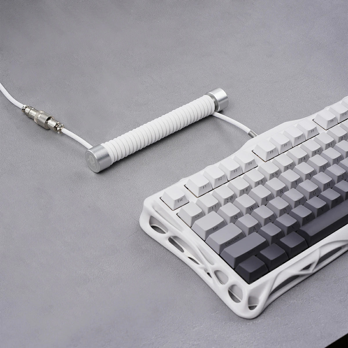 GravaStar Coiled Aviator USB Cable White studio setup view showing 4-pin GX12 aviator connector, TPU EVA double-sleeved white braided cable body, GravaStar tactical logo emblem ring, connected to white Mercury K1 keyboard.