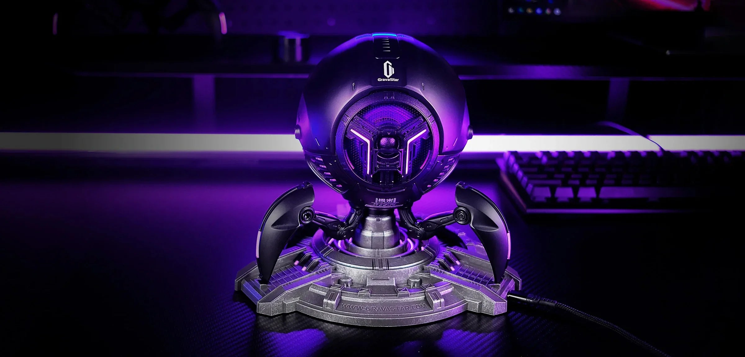 GravaStar Mars Pro Black Bluetooth speaker desktop overlay banner featuring matte black zinc alloy shell, shock-absorbing tripod legs, 20-watt dual speaker system with passive bass radiator, DSP equal-loudness contour, and dynamic purple RGB lighting effect.