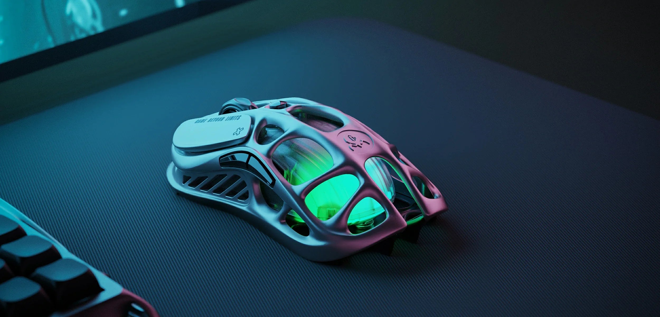 GravaStar Mercury M1 Pro Wireless Gaming Mouse Gunmetal Gray desk setup close-up view displaying magnesium alloy skeletal frame, GAME BEYOND LIMITS text, side buttons, PAW3395 sensor, and green RGB backlighting.