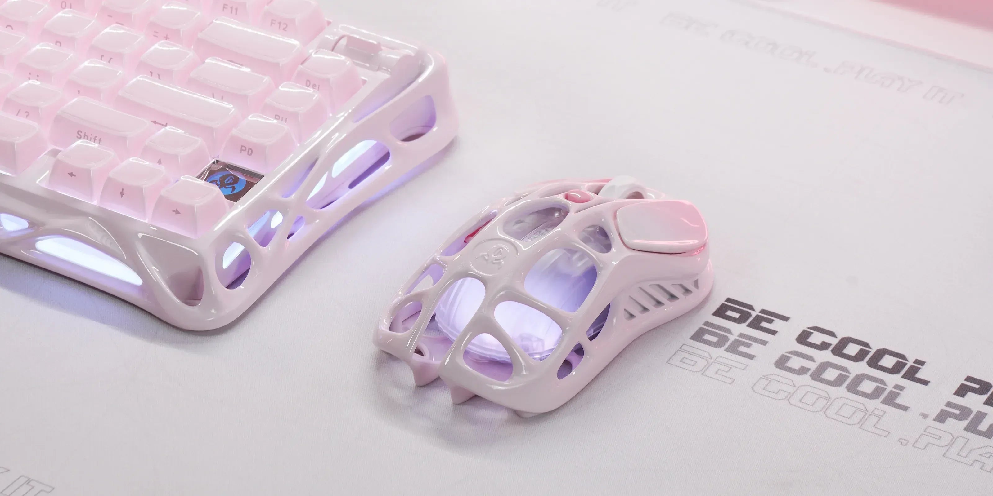 GravaStar Mercury M1 Pro Special Edition Sakura Pink wireless gaming mouse displayed on white desk setup alongside Mercury K1 Pro Sakura Pink mechanical keyboard, featuring 88g magnesium alloy skeletal frame, PAW3395 26K DPI optical sensor, and pink RGB lighting.