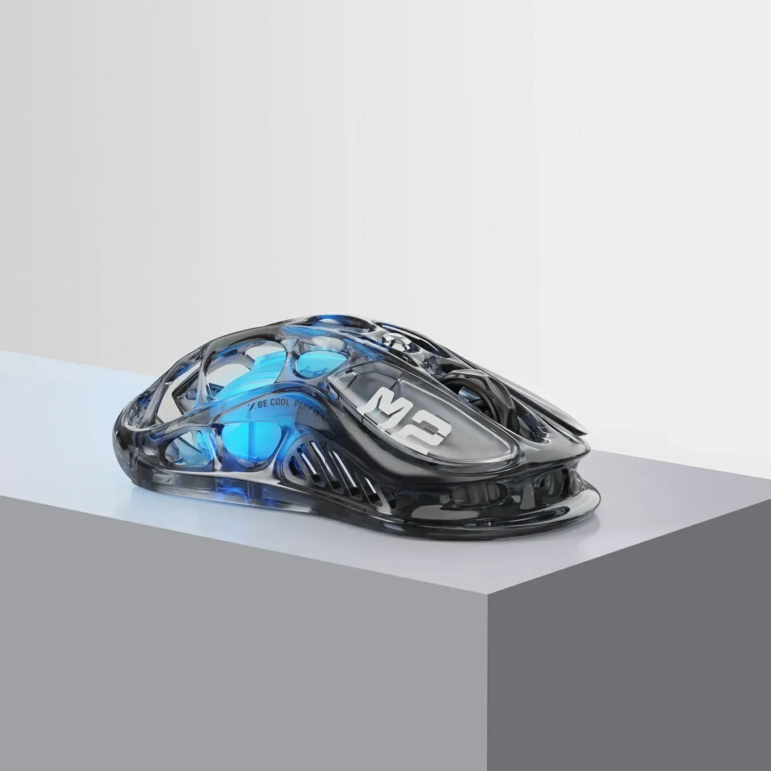 GravaStar Mercury M2 Transparent Black wireless gaming mouse close-up highlighting see-through crystal skeletal housing with tactical typography, PAW3395 26K DPI optical sensor, 79g lightweight frame, and ice blue RGB lighting.