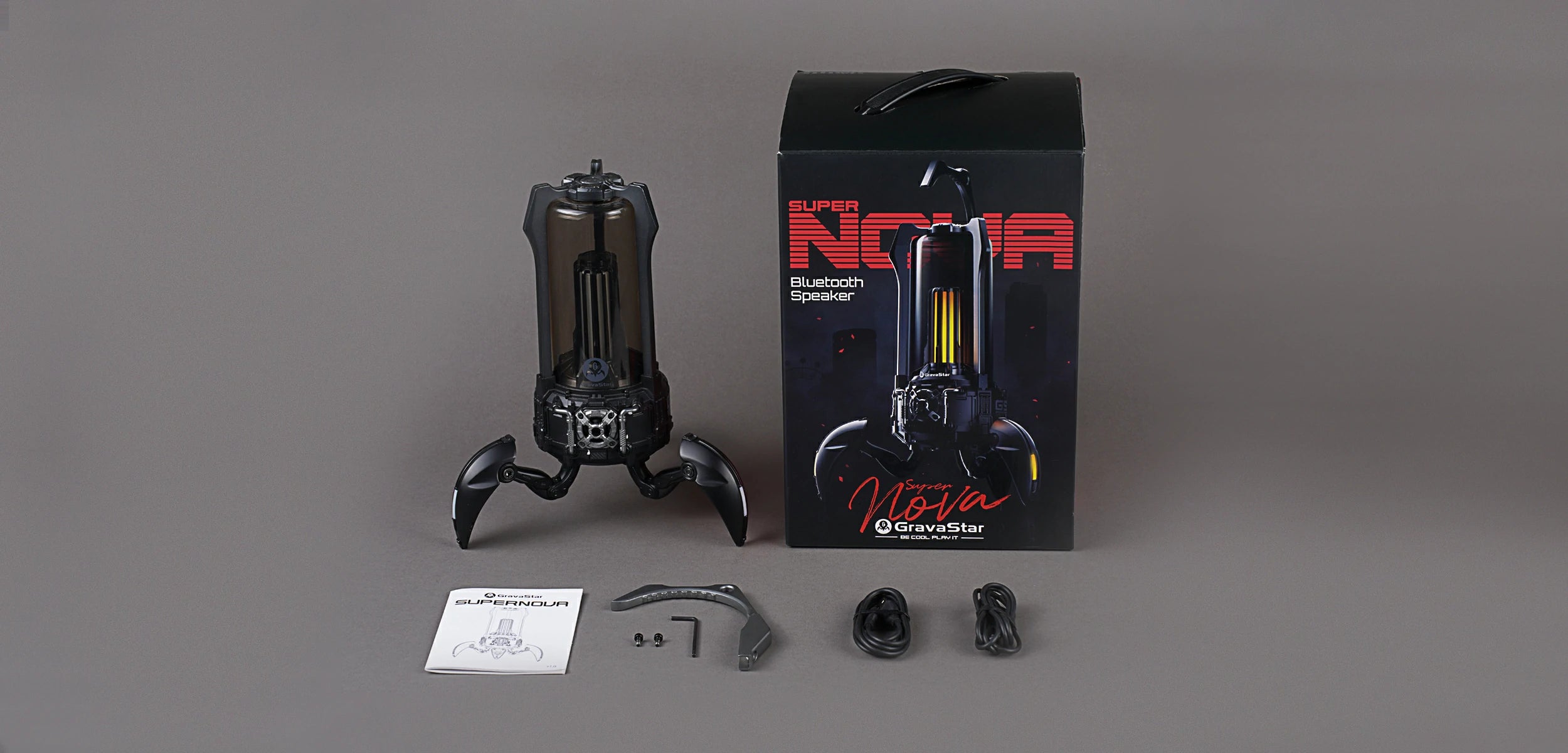 GravaStar Supernova Matt Black mecha lantern Bluetooth speaker in the box accessories including official packaging box, removable carry handle, 3.5mm auxiliary audio cable, USB-C charging cable, and user manual.
