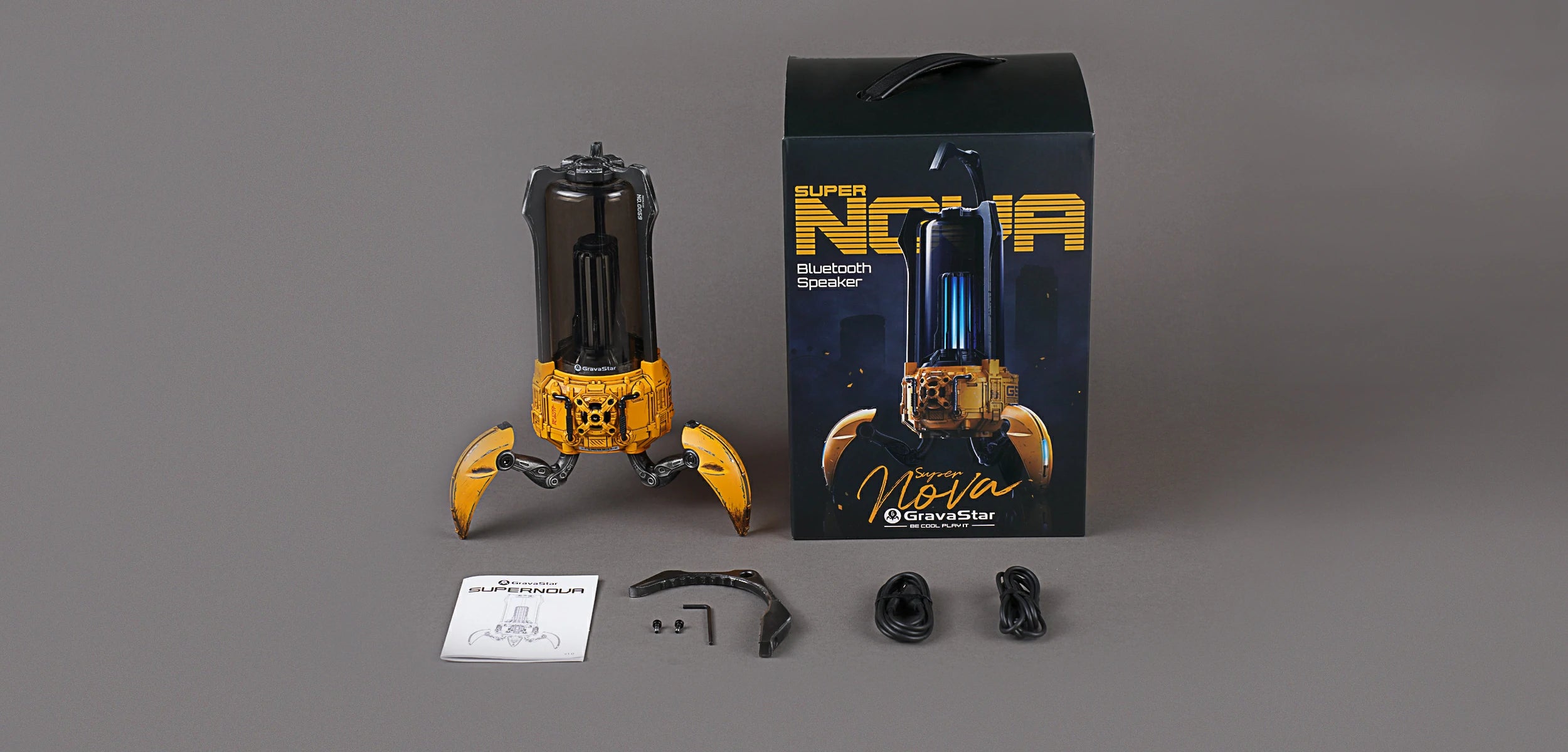 GravaStar Supernova War Damaged Yellow handcrafted mecha lantern Bluetooth speaker in the box accessories including official packaging box, removable carry handle, 3.5mm auxiliary audio cable, USB-C charging cable, and user manual.