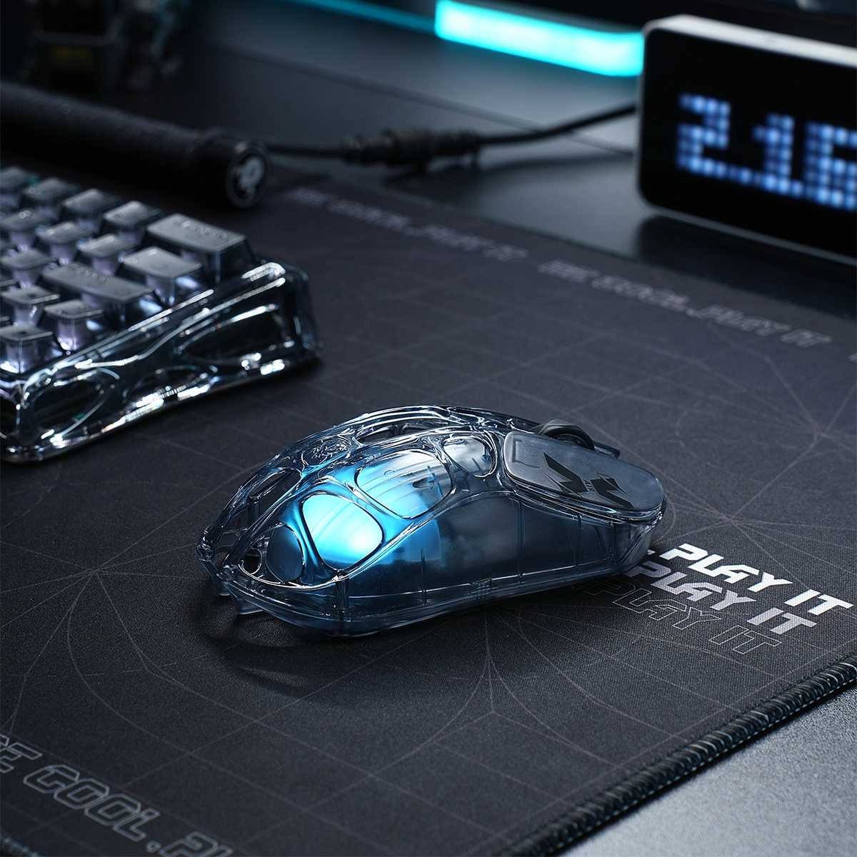 GravaStar V60 and X Air 8000Hz Gaming Set Mercury X Air wireless gaming mouse desktop view showing 56g transparent skeletal frame and ice blue RGB lighting on GravaStar deskmat.