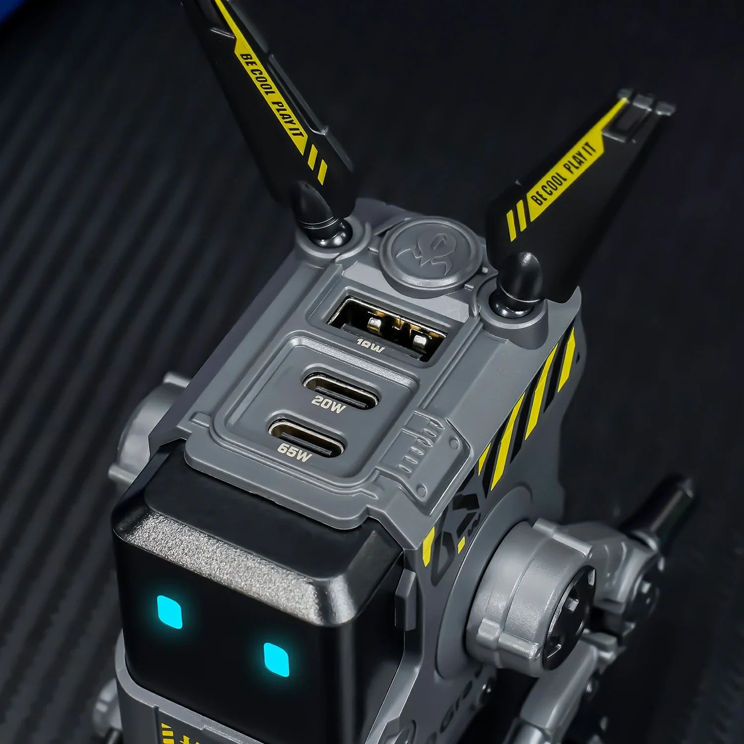 GravaStar Alpha65 Charcoal Gray 65W GaN fast charger top close-up view showing 3 USB ports (2 USB-C + 1 USB-A), tactical antennas with BE COOL PLAY IT slogan, ice blue RGB eyes, and sleek matte black mecha frame, perfect paired with Mercury X Air Onyx Crystal mouse and Mercury K1 Stealth Black keyboard.
