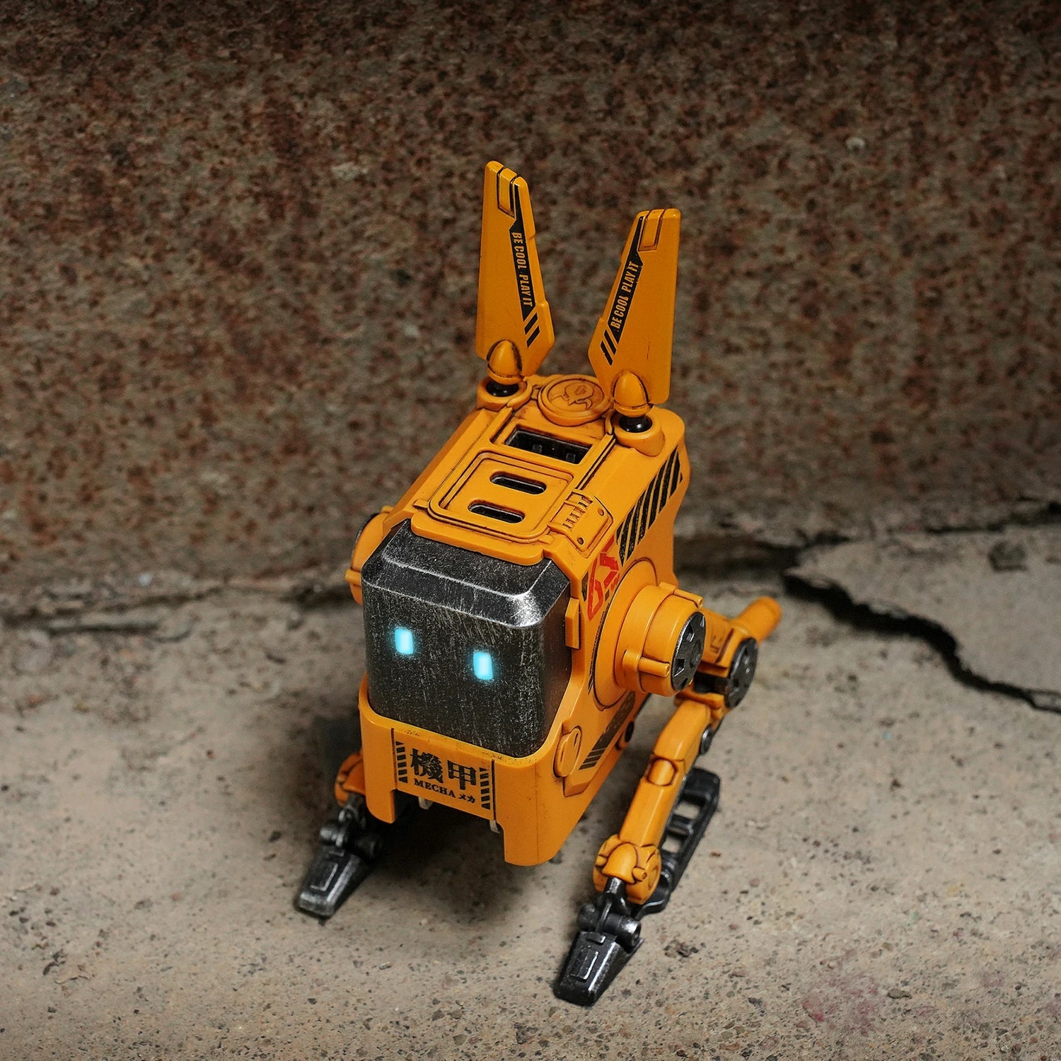 GravaStar Alpha65 War-Damaged Yellow handcrafted 65W GaN fast charger concrete standing view featuring authentic weathered yellow finish, transformable tripod stand, dual antennas, ice blue RGB eyes, and 3 USB ports, perfect paired with Mercury X Pro Yellow mouse and Mercury K1 Pro Yellow keyboard.