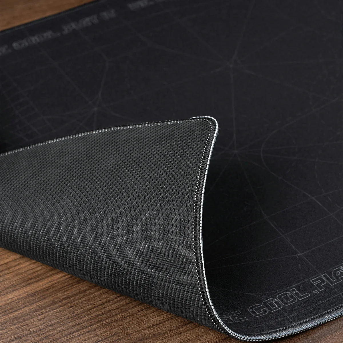 GravaStar Gaming Mouse Pad Black studio non-slip base and stitched edges view featuring high-density anti-slip rubber bottom, durable stitched edge border, and waterproof fabric, perfect paired with Mercury V75 Pro Stealth Black keyboard and Mercury M1 Pro Gunmetal Gray gaming mouse.